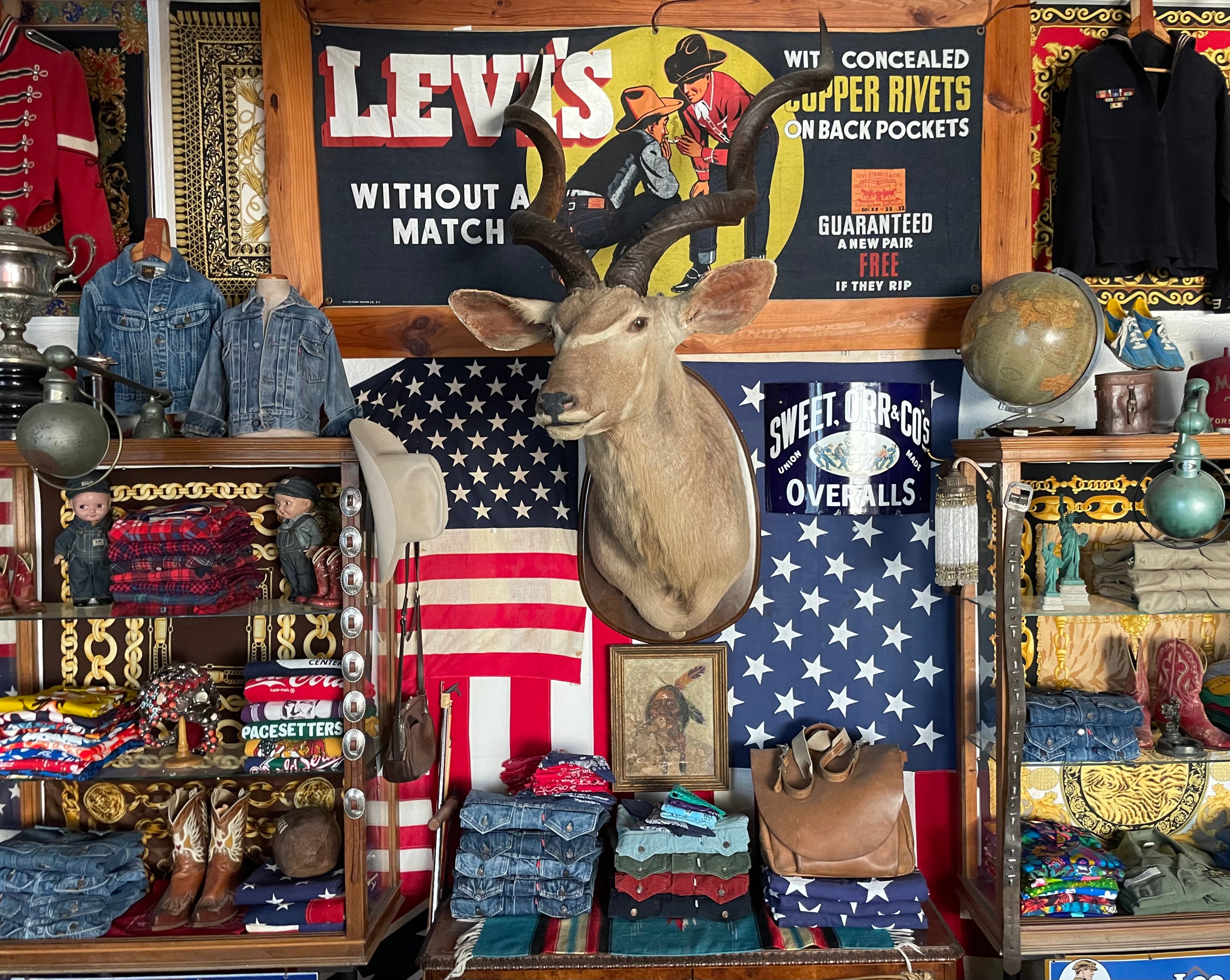 Authentic American vintage denim collection with Levi’s banner, folded jeans, cowboy boots, and rustic decor at USA Vintage BCN in Barcelona